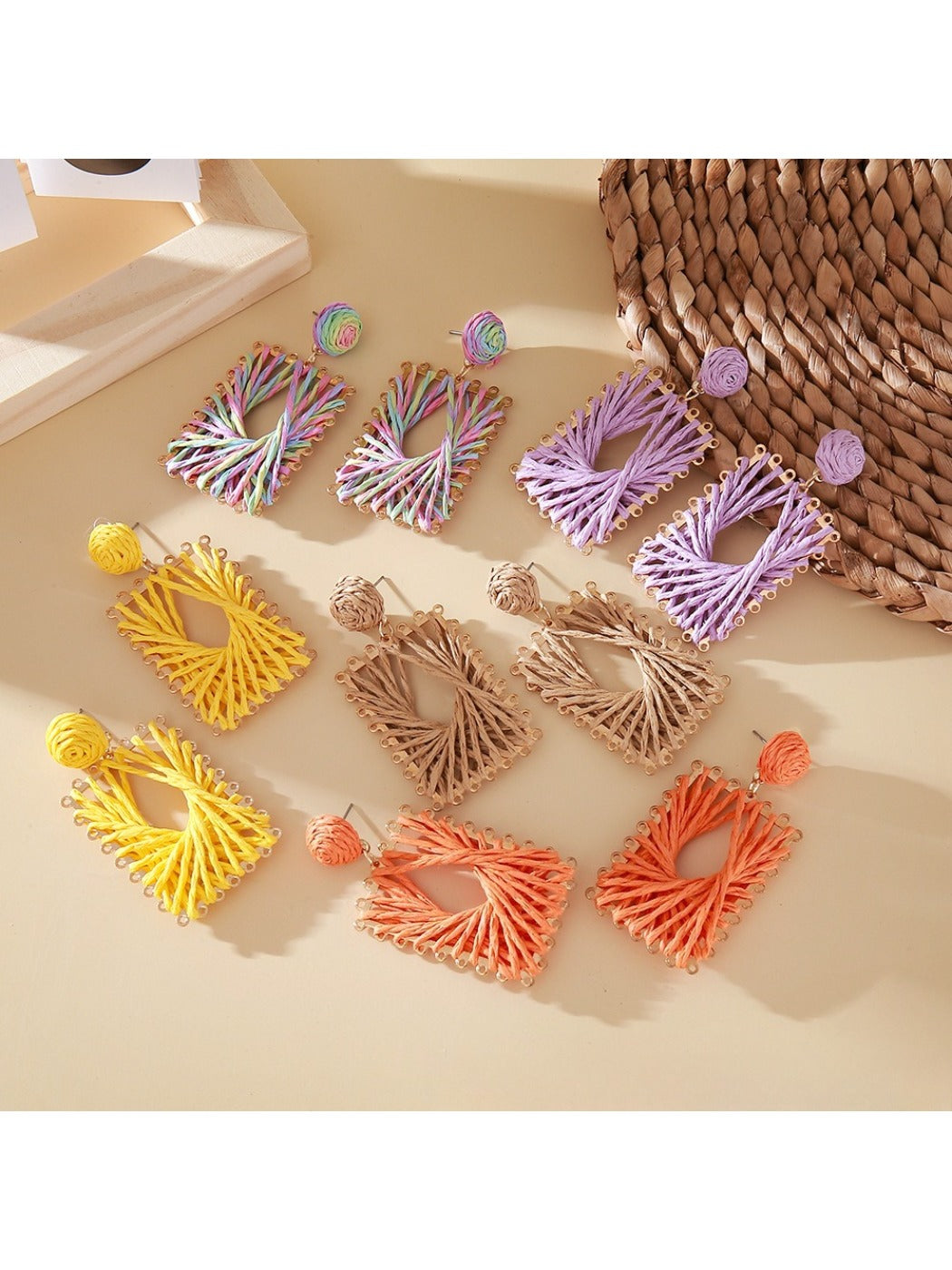Close-up of Earedge raffia wrapped square earrings on white background