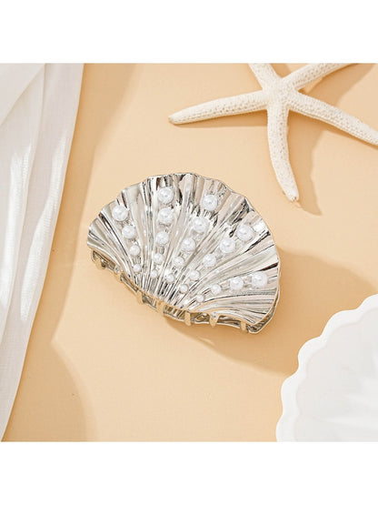 Beau seashell hair clip worn in blonde hair against a beach background