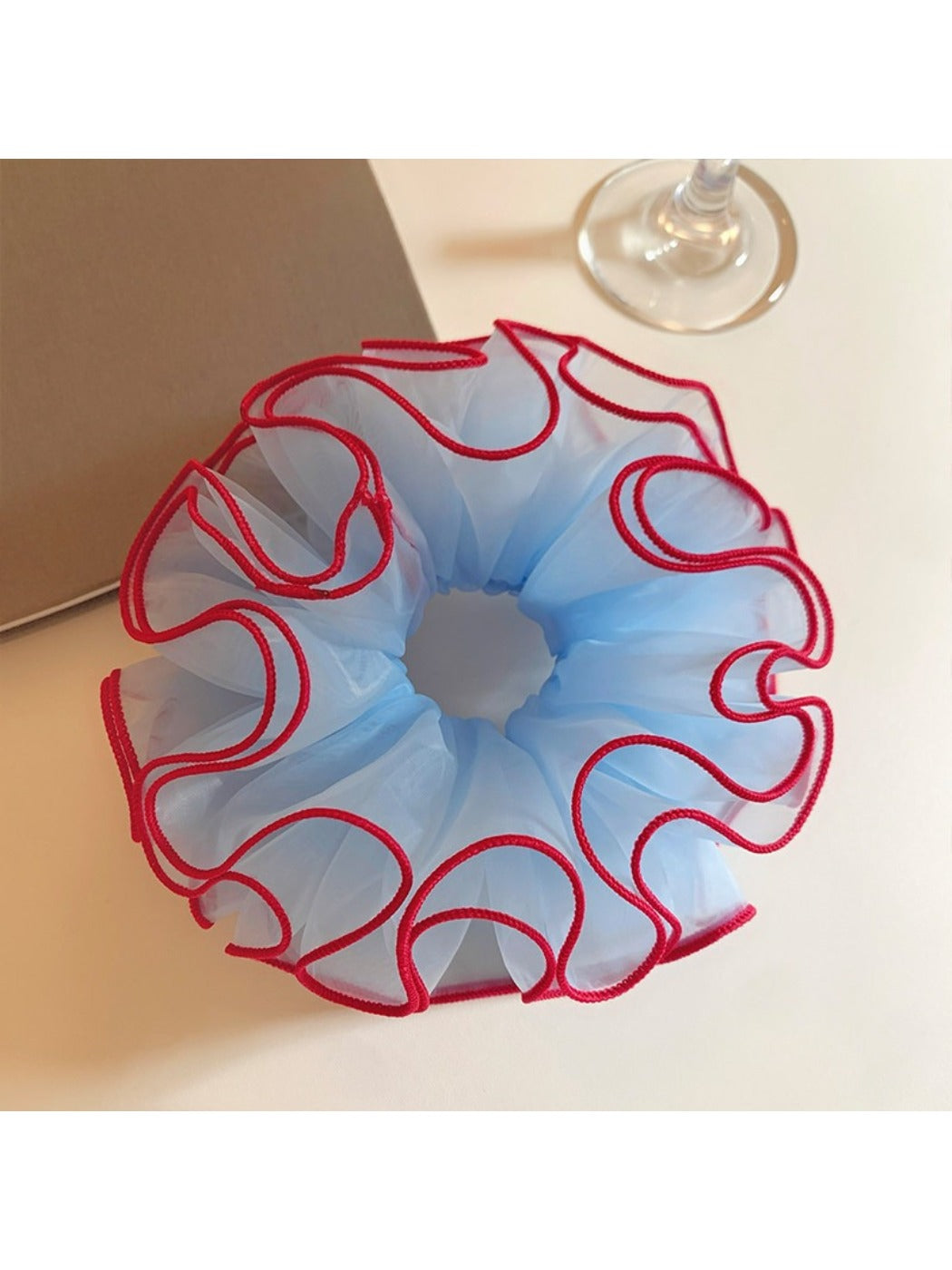 Blue tulle scrunchie with red trim on a white background