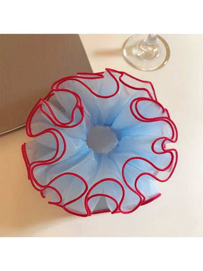 Blue tulle scrunchie with red trim on a white background
