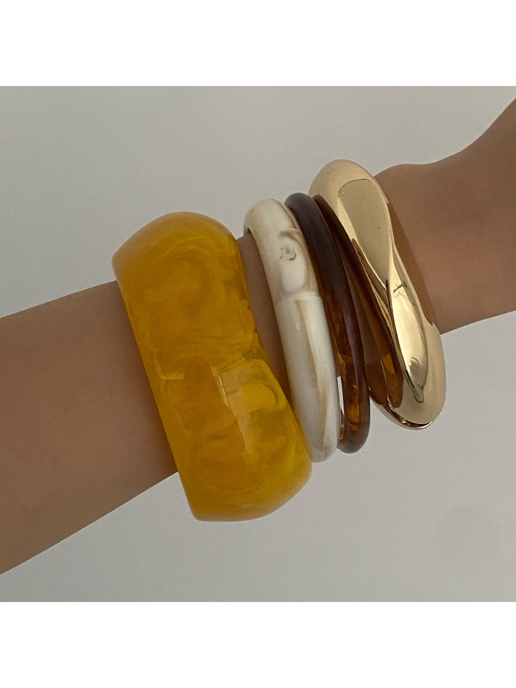 Close-up of Lovra wide round bangle bracelet highlighting its rounded edges and shiny finish