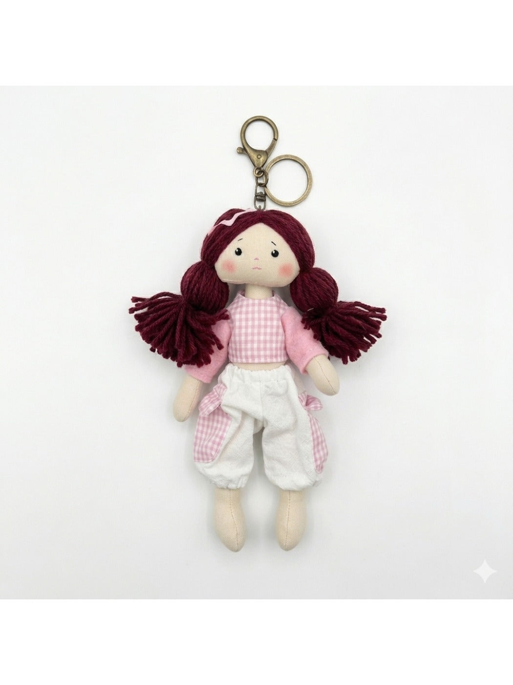 Fabric yarn doll keychain displayed with other colorful keychains on a wooden surface