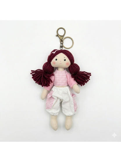 Fabric yarn doll keychain displayed with other colorful keychains on a wooden surface