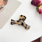 Beau claw clip in black held between fingers showing size and shape