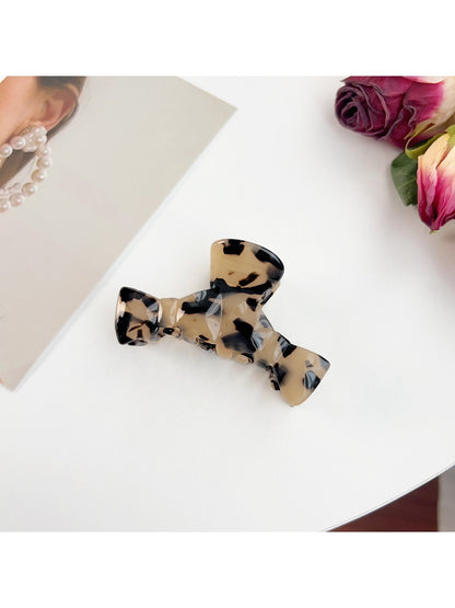 Beau claw clip in black held between fingers showing size and shape