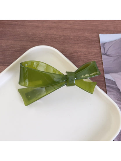 Beau acetate bow hair clip held in hand to show size and shape