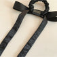 Satin bow hair tie displayed on a wooden surface with natural lighting