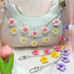 Flower pendant bag charm attached to a beige handbag handle