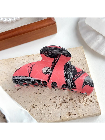 Beau hair claw clip held in hand showing size and crow pattern details