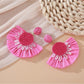 Pair of Earedge minimalist fan shaped drop earrings laid flat on a textured surface