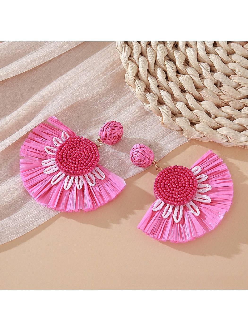 Pair of Earedge minimalist fan shaped drop earrings laid flat on a textured surface