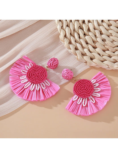 Pair of Earedge minimalist fan shaped drop earrings laid flat on a textured surface