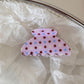 Beau pink hair clip with white polka dots next to matching pink accessories