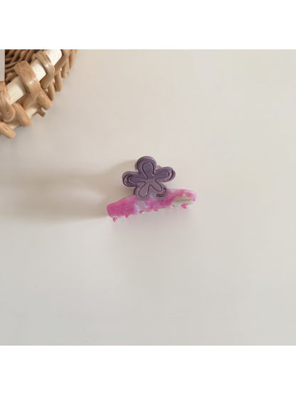 Beau flower hair clip worn in long brown hair styled in loose waves
