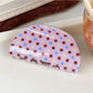 Beau crescent pink claw clip with white polka dots angled to show clip curvature