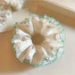 White tulle double scrunchie with green trim on a white background