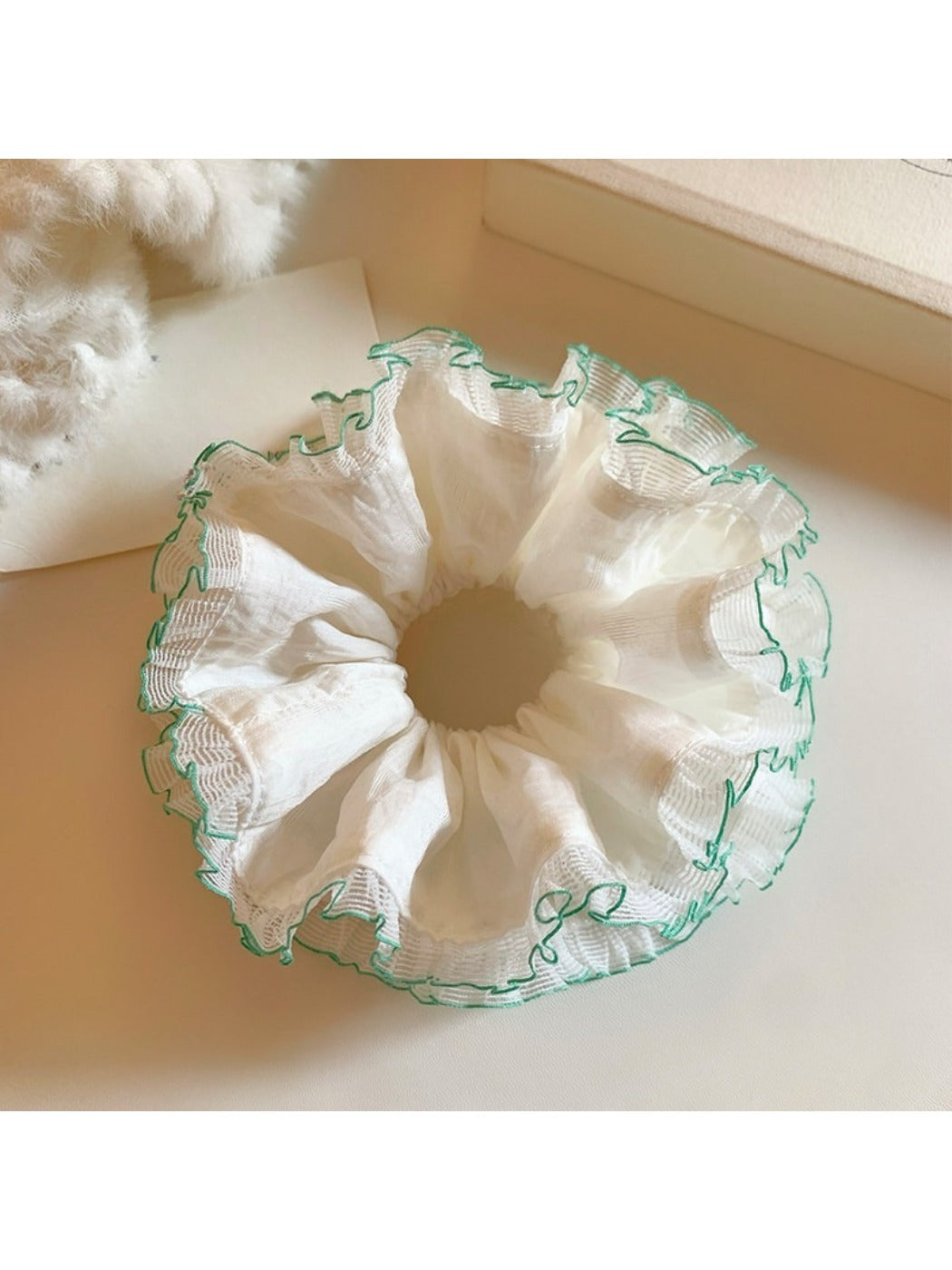 White tulle double scrunchie with green trim on a white background