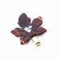 Beau leaf hair clip positioned on a wooden surface with natural light
