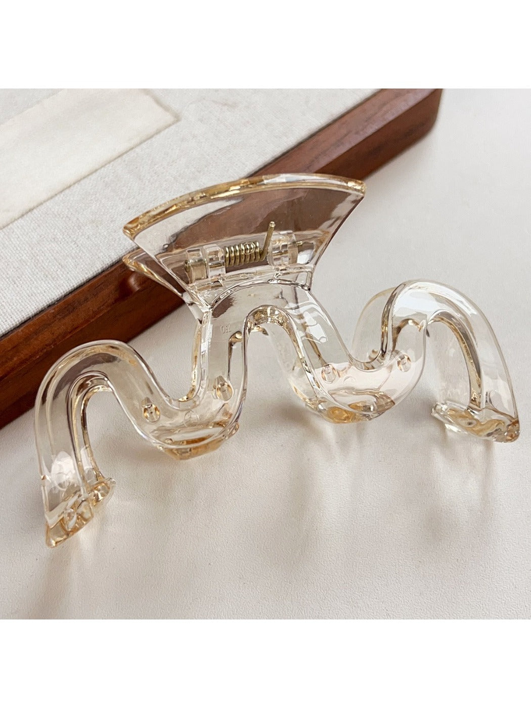 Model styling hair with Beau wave-shaped hair claw clip in natural light