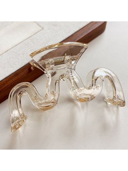Model styling hair with Beau wave-shaped hair claw clip in natural light