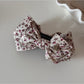 Beau floral print bow hair clip placed next to matching accessories