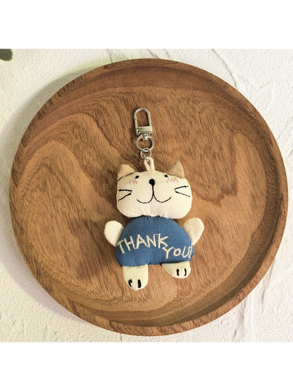 Cat charm keychain held between fingers showing size and detail