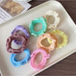 Close-up of colorful ruffled hair ties arranged in a circle on a white background