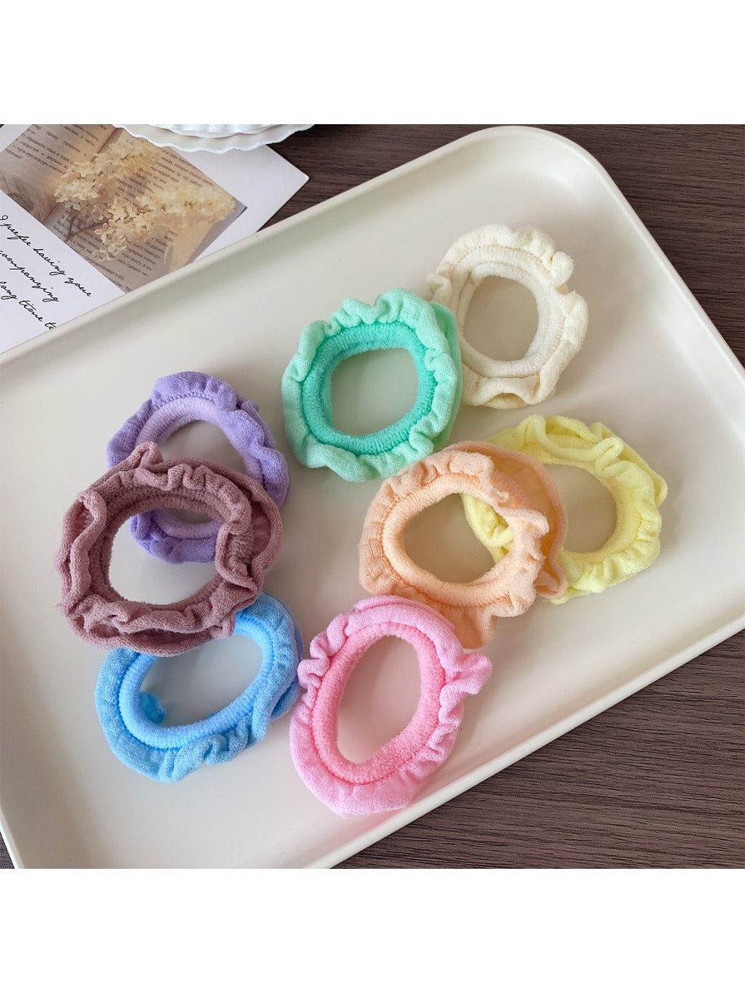 Close-up of colorful ruffled hair ties arranged in a circle on a white background