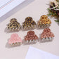 Beau hair clip featuring leopard print fabric and gold clasp held in hand