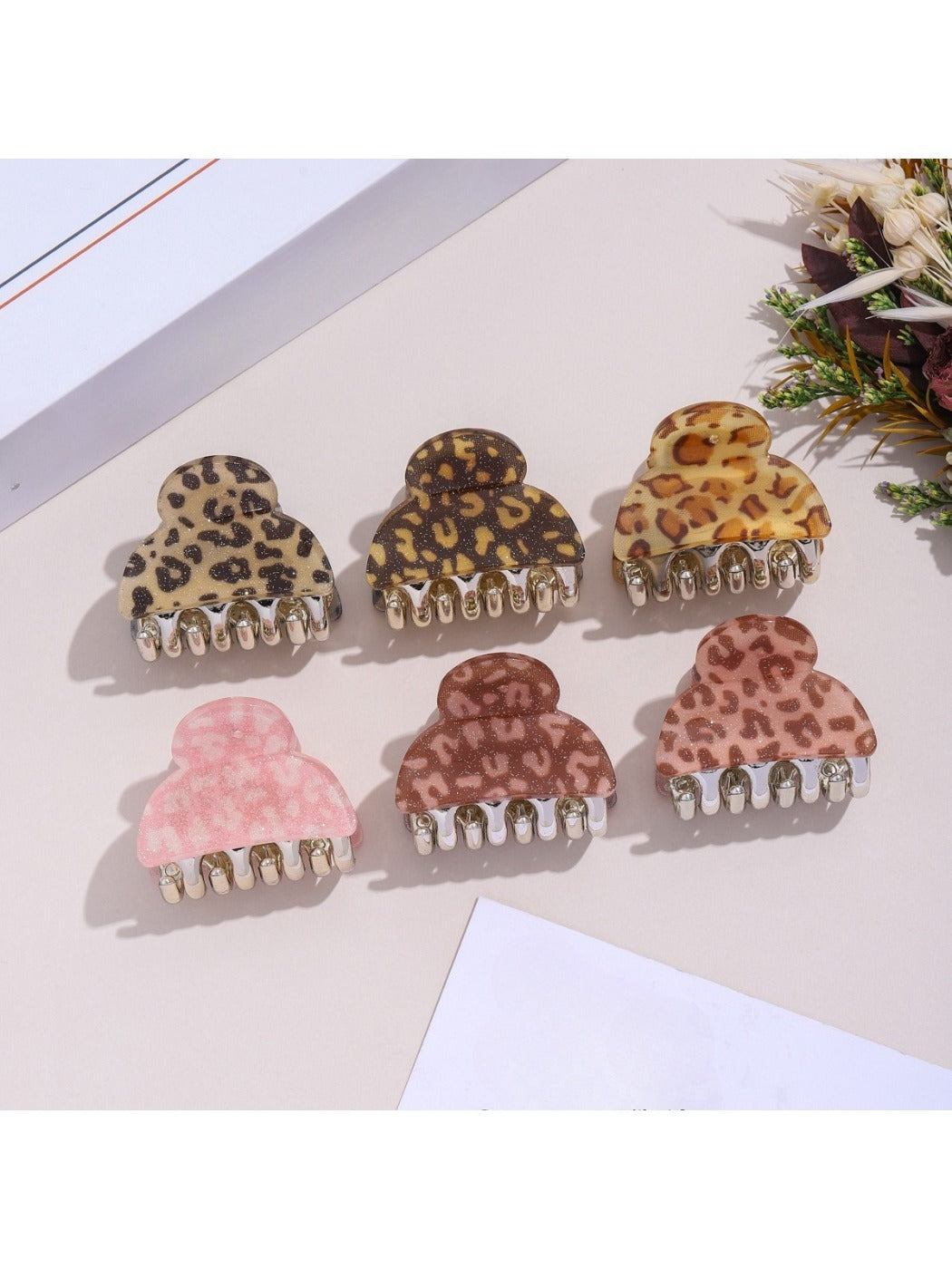 Beau hair clip featuring leopard print fabric and gold clasp held in hand