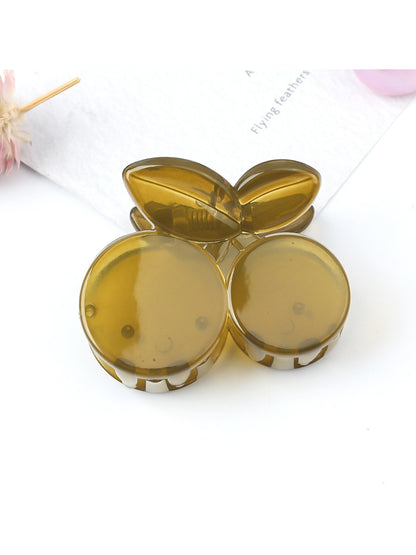 Beau cherry claw clip placed on a wooden surface with natural light