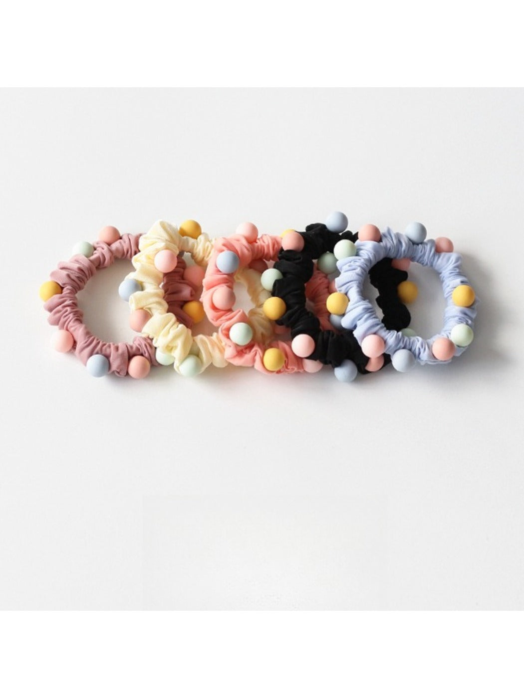 Set of sweet pastel-colored beaded hair ties displayed on a wooden surface