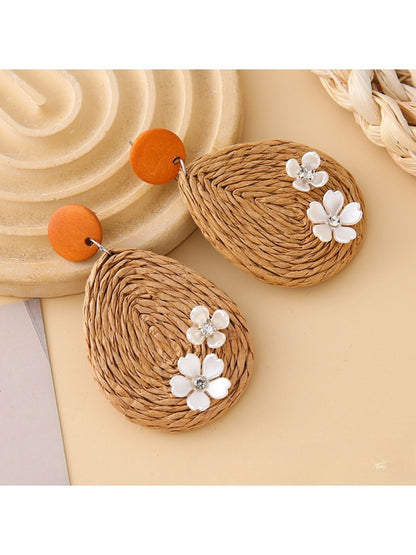 Pair of Earedge raffia teardrop earrings placed on a natural fabric surface