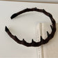 Side view of beige corduroy headband highlighting fabric texture and elastic