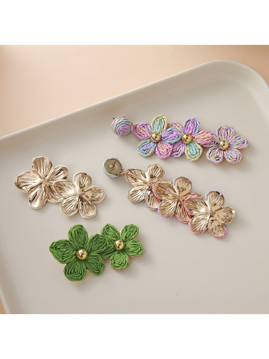 Pair of earedge flower shaped raffia drop earrings displayed on white background