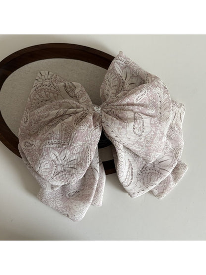 Beau chiffon bow shaped claw clip worn in model's hair from side angle