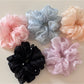 Multiple Gifty scrunchies displayed on a white surface highlighting fabric details