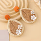 Earedge raffia teardrop earrings displayed with green leaves in the background