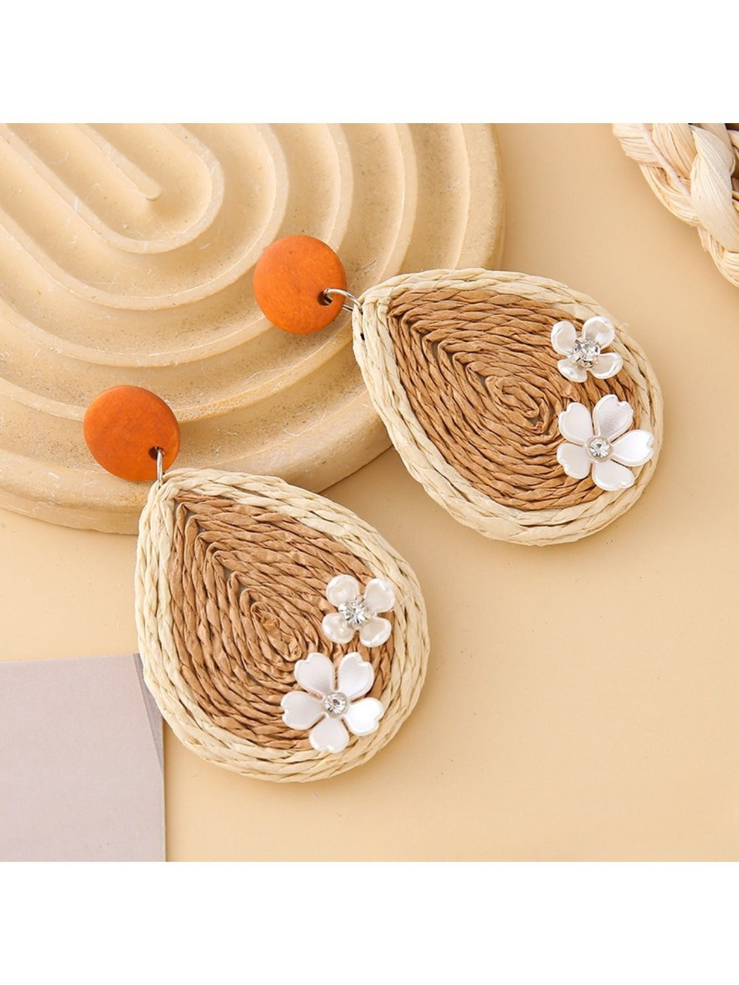 Earedge raffia teardrop earrings displayed with green leaves in the background