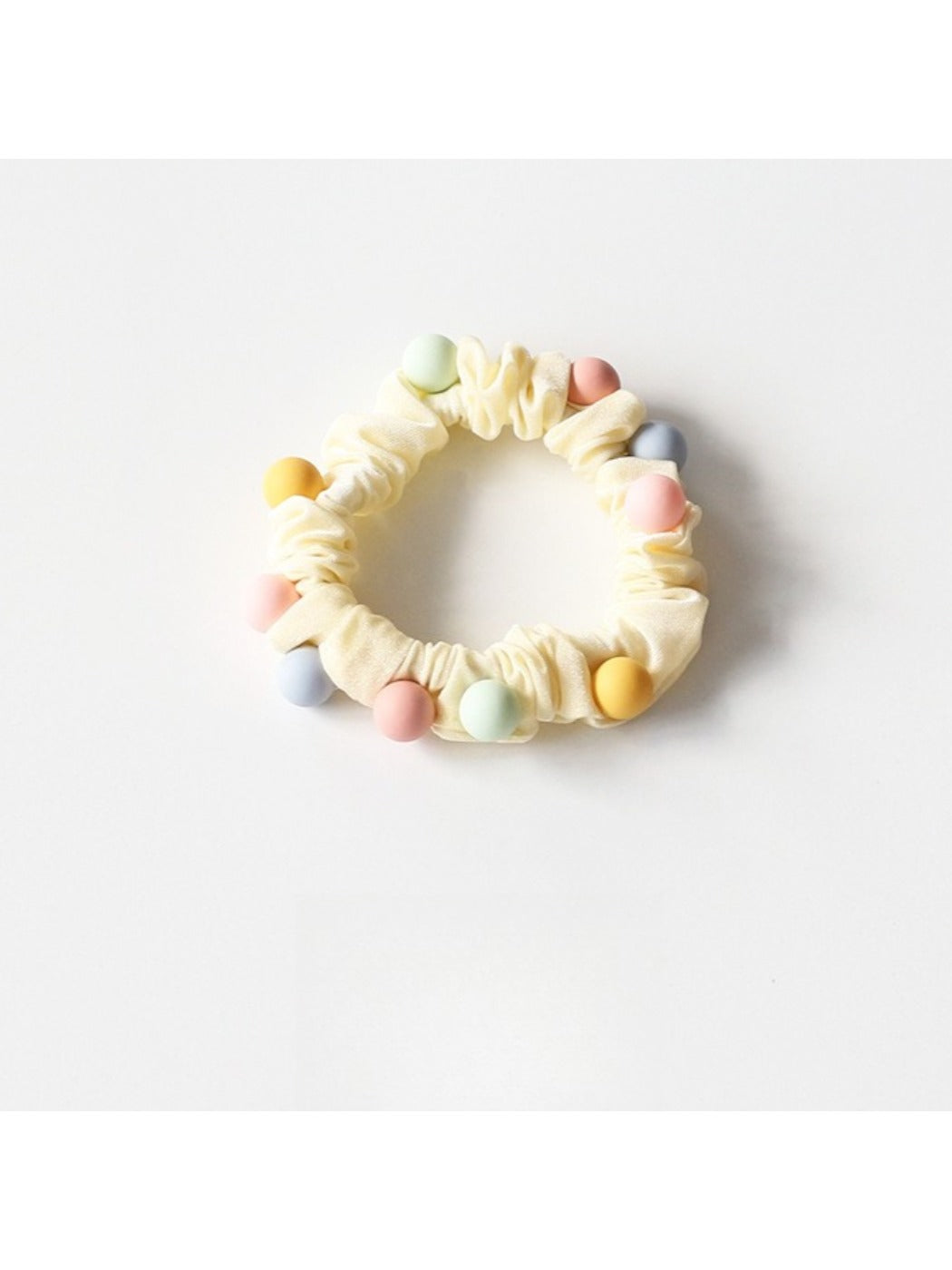 Beaded hair ties in soft pastel shades laid out neatly on a light fabric