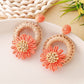 Earedge raffia daisy stud earrings placed next to green leaves for styling