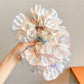 Close-up of Gifty sweet tiny floral high stretch scrunchie with pastel flowers on fabric