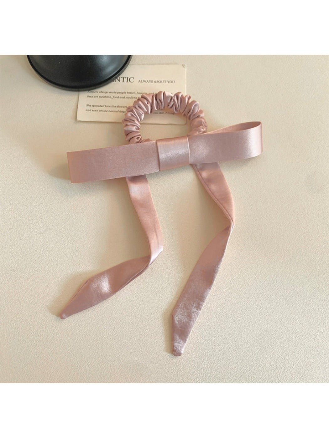 Hair tie with bow detail wrapped around a ponytail on a model with brown hair