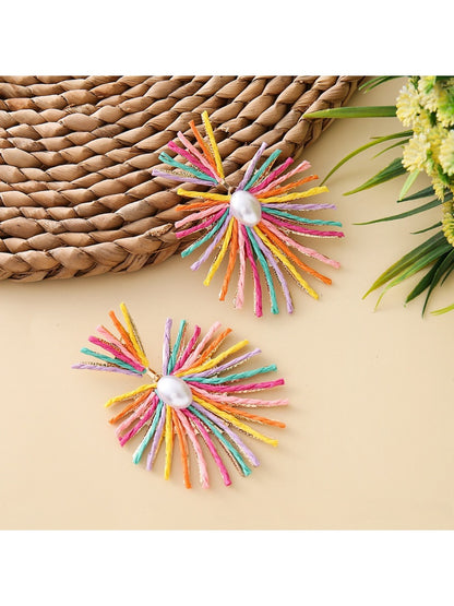 Pair of raffia drop earrings displayed on a wooden surface