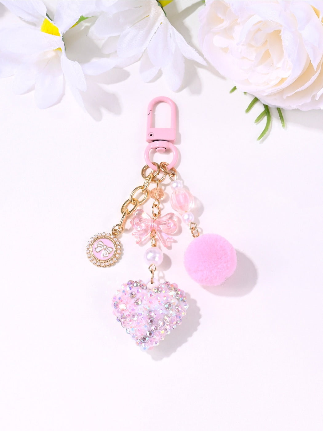 Pink heart keychain displayed on a wooden surface with soft lighting