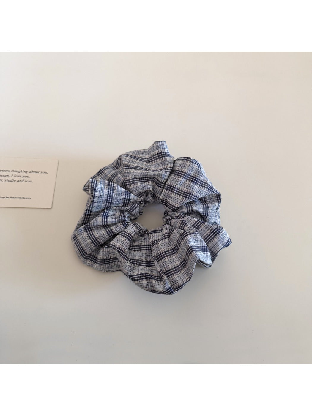 Flat lay of Gifty plaid scrunchie alongside matching minimalist accessories
