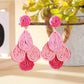Earedge raffia drop earrings arranged with green leaves for a natural aesthetic