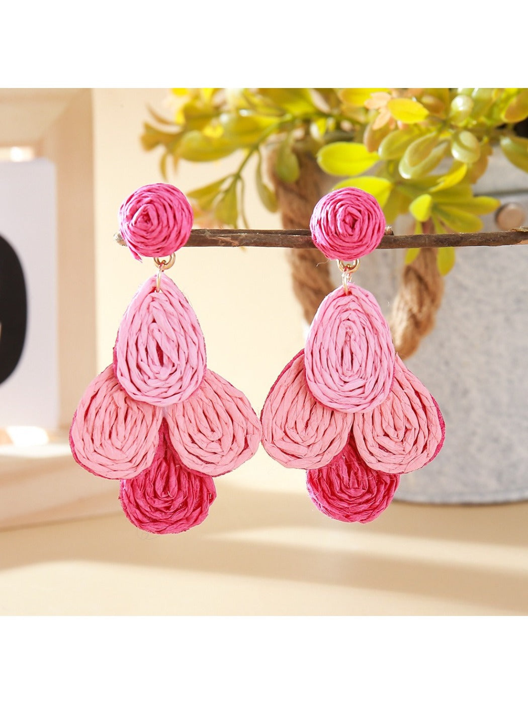Earedge raffia drop earrings arranged with green leaves for a natural aesthetic
