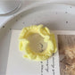 Multiple colorful ruffled hair ties spread out on a pastel background