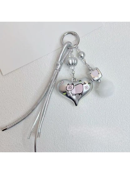Silver heart keychain hanging from a bag zipper with natural lighting
